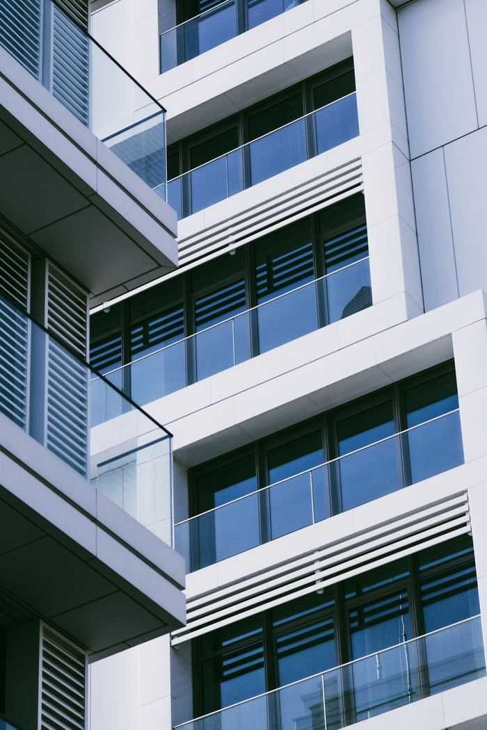 Contemporary urban apartment building facade with glass balconies and geometric design.